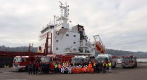 Group shot in front of firetrucks and the ship Pekin